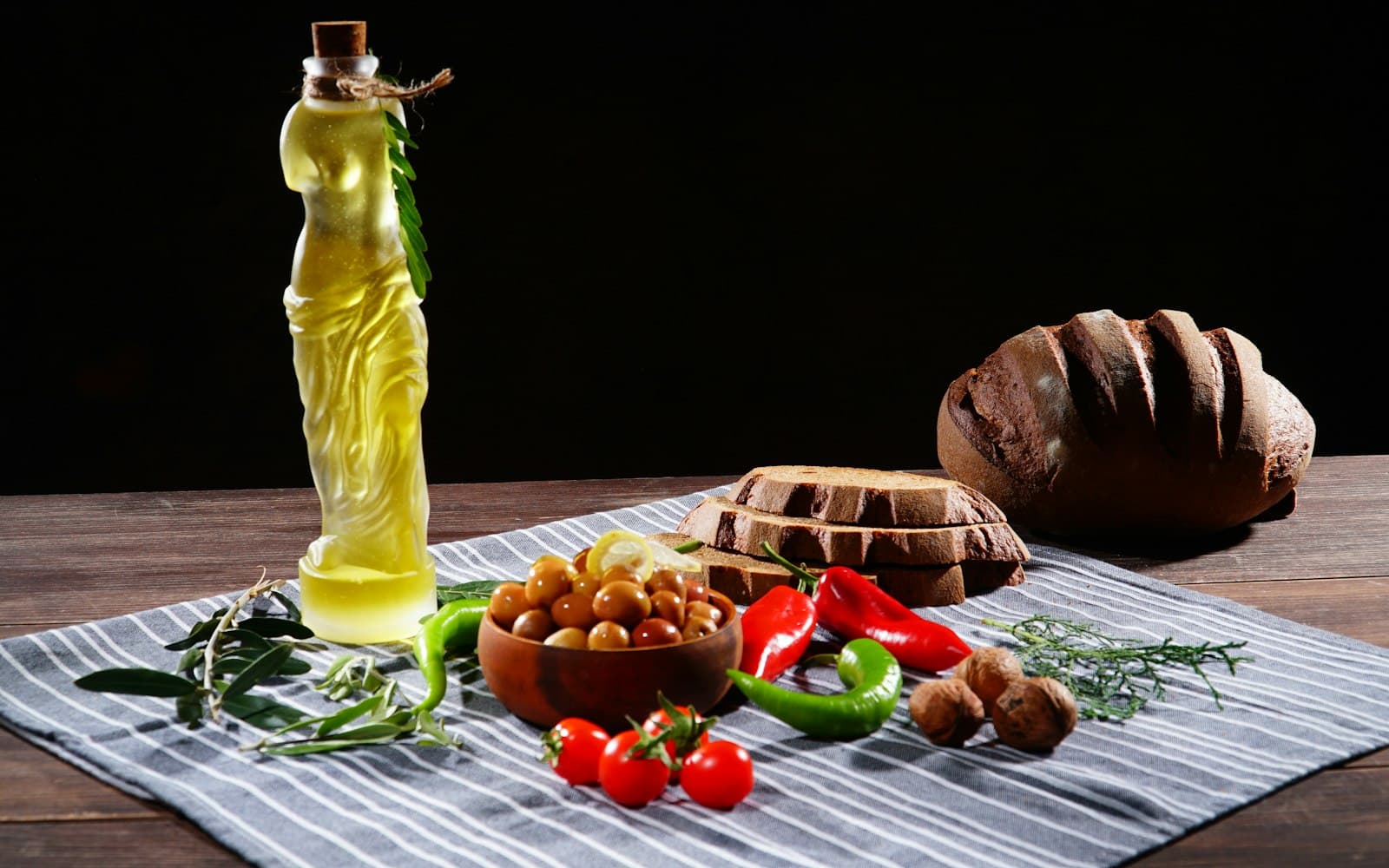 A Mediterranean table set with olive oil, bread and fresh vegetables