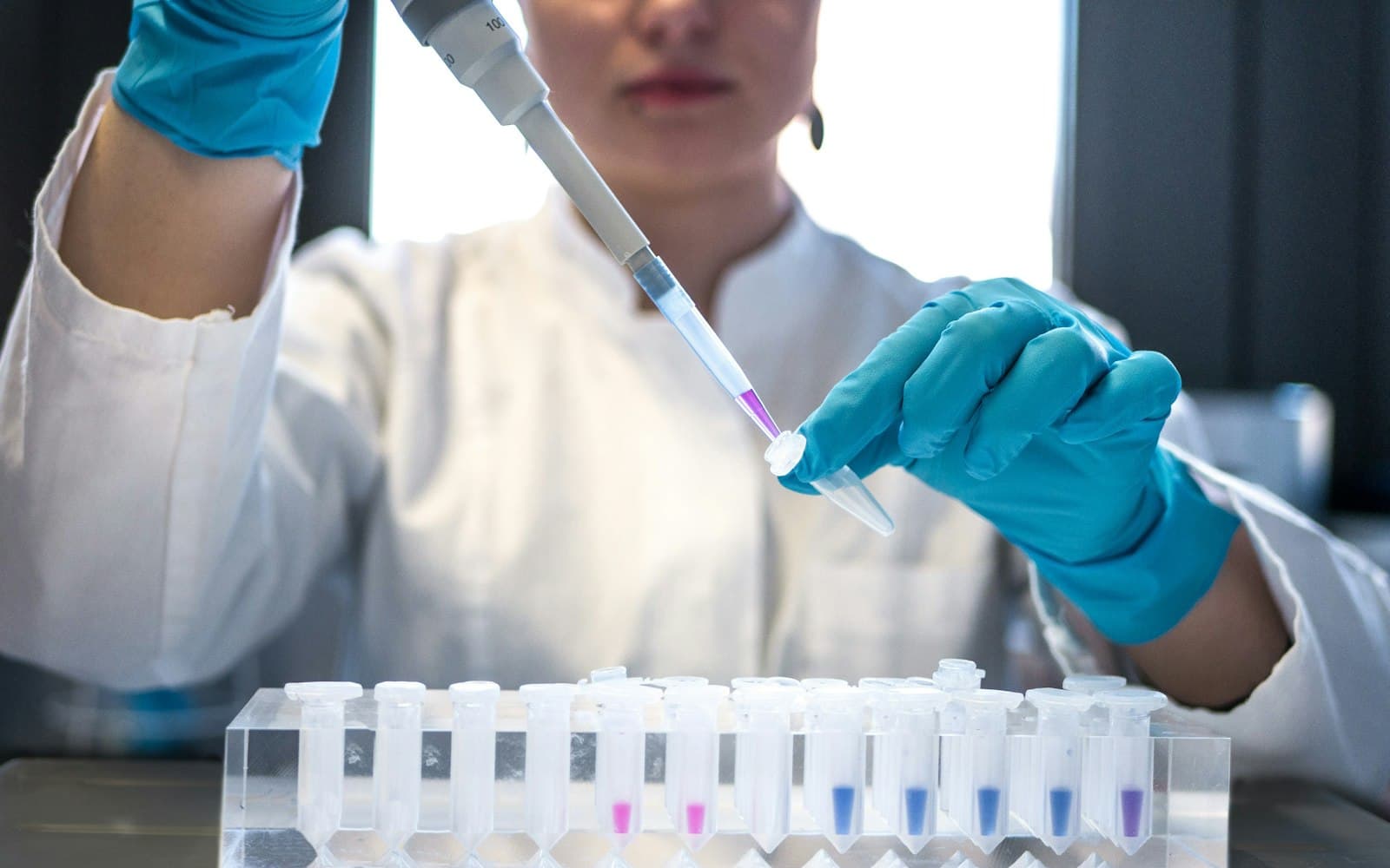 A researcher preparing a sample with a pipette in a laboratory