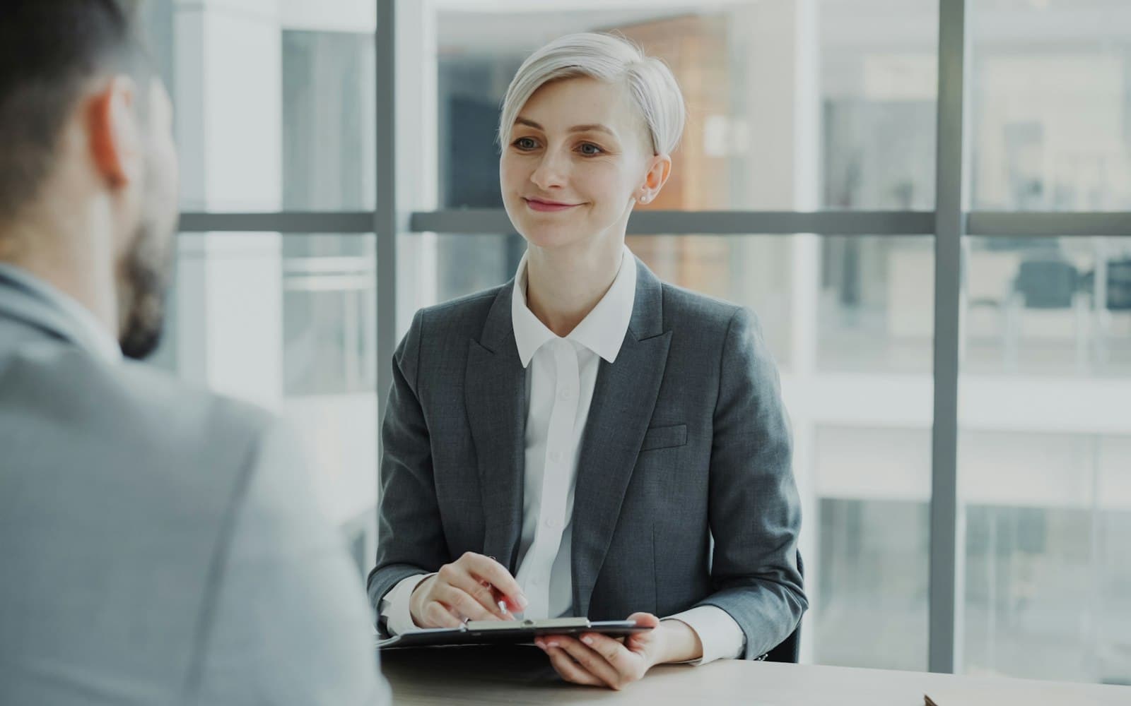 A woman smiling and taking notes during an interview